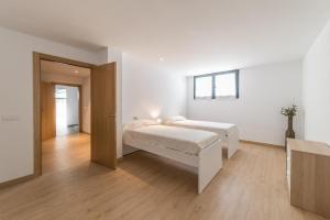 ein weißes Schlafzimmer mit einem Bett und Holzboden in der Unterkunft Villa Margarita in L'Escala