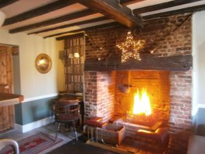 a fireplace in a room with a couch and a chair at The Barleycorn Inn in Collingbourne Ducis