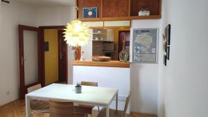 a dining room with a white table and a kitchen at Fedra Apartment in Zrenjanin