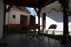 three chairs and a table in a yard with a house at Fedra Apartment in Zrenjanin
