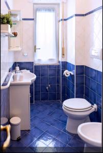 Un baño con azulejos azules, inodoro y lavabo. en La casetta di Ilma, en Vietri