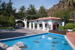 a hotel with a blue pool in front of a building at Villaggio Turistico La Mantinera - Appartamenti de Luxe in Praia a Mare