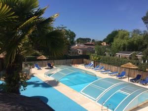 a large swimming pool with chairs and a fence at Appartement Cosy 1 - Camping Les Ecureuils in Arès