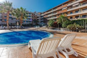 une piscine avec deux chaises et un hôtel dans l'établissement Balcon de Los Gigantes 2A037, à Puerto de Santiago