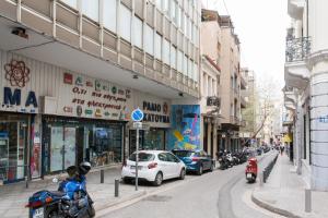 eine Stadtstraße mit Autos und Motorrädern auf der Straße in der Unterkunft Dynasta Central Suites in Athen