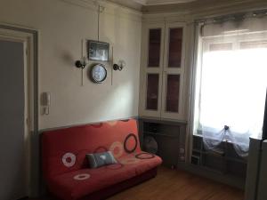 Habitación con sofá rojo y reloj en la pared en Studio des alpes, en La Mure