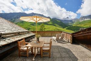 eine Terrasse mit einem Tisch, Stühlen und einem Sonnenschirm in der Unterkunft Hotel Stoffel - adults only in Arosa