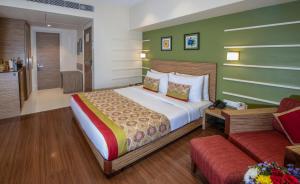 a bedroom with a large bed and a couch at Hotel Bawa Suites in Mumbai