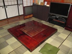 een houten tafel in het midden van een kamer met een tv bij Minpaku TOMO 8 tatami room / Vacation STAY 3707 in Hida