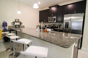 a kitchen with a stainless steel refrigerator and white stools at A - New 4 Bedroom Home - 5 Miles to Disney - Free Water Park - Private Pool in Kissimmee