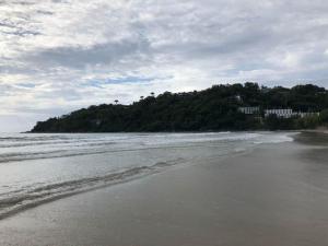 una playa de arena con una isla en el agua en Condominio residencial Ubatuba, en Ubatuba