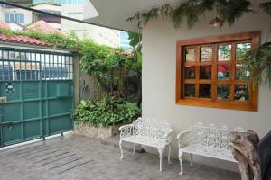 two white benches sitting next to a door at Hostal Macaw in Guayaquil