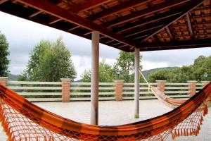a hammock on a deck with a fence at Pousada Sol Da Montanha in Jardim Sun Valley