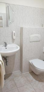 a white bathroom with a sink and a toilet at Penzion PIANO & Apartment PIANO in Sokolov