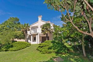 a white house with palm trees and bushes at Liliana in Medulin * Istrien in Medulin