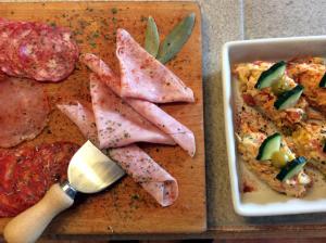 a cutting board with ham and a plate of food at Los Cuatro Vientos B&B in Torre del Rico