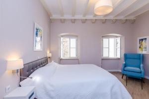 a white bedroom with a bed and a blue chair at Villa Flores Room in Dubrovnik