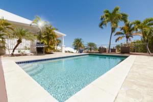 a swimming pool with palm trees in front of a house at VILLA SAPHIR in Saint Martin