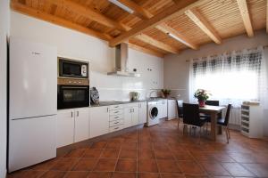 a kitchen with white cabinets and a table and a dining room at Las Casas de Pecheye in Bocigas