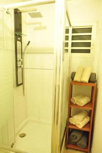 a bathroom with a shower and a towel shelf with towels at Les Héliconias Résidence cosy et calme in Les Abymes