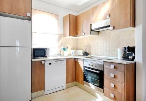 a kitchen with wooden cabinets and white appliances at Pueblito La Zenia Beach in Orihuela Costa +21 photos