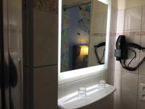 a bathroom with a phone on a sink and a mirror at Hôtel de L'Avenue in Tarbes