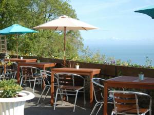 a row of tables and chairs with an umbrella at Chough's Nest Hotel in Lynton