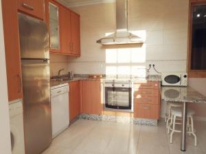 a kitchen with wooden cabinets and a stainless steel refrigerator at A&L Centro in Viveiro