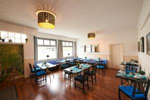 a dining room with tables and blue chairs at Hotel Wurster Kroog in Bremerhaven