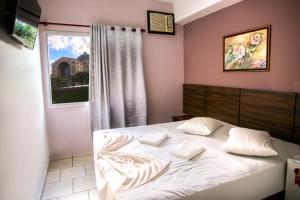 a bedroom with a white bed with a window at Hotel Faenician in Aparecida