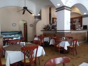 a restaurant with white tables and chairs and a counter at Hotel Virreynal in Córdoba