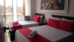 twee bedden in een kamer met rood en wit bij Hotel Girón Plaza in Girón