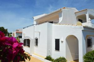 a white house with purple flowers in front of it at Casa Maricel in Praia do Carvoeiro