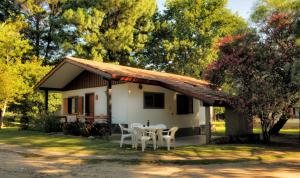 a small white house with a table and chairs at Cabañas Alpendorf in Villa General Belgrano