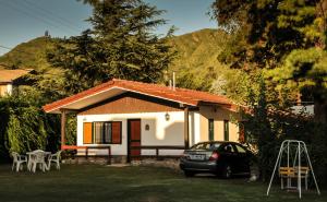 a small house with a car parked in front of it at Cabañas Alpendorf in Villa General Belgrano