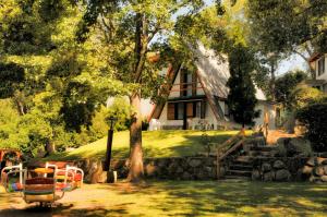 a house with a tree and a bench in the yard at Cabañas Alpendorf in Villa General Belgrano