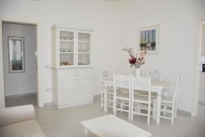 a white dining room with a white table and chairs at casa Pepi in Olbia