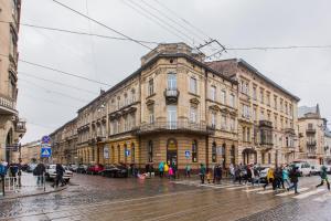 a group of people walking on a street in front of a building at Baker's street in Lviv