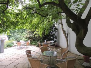 a patio with tables and chairs under a tree at CVJM Düsseldorf Hotel & Tagung in Düsseldorf