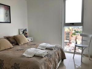 um quarto com uma cama e uma grande janela em ALOHA Güemes Premium, 2 dorm con Vista a las Sierras em Córdoba