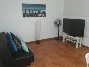 sala de estar con sofá y TV de pantalla plana en Casita con Barbacoa, en La Frontera