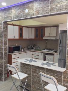 een keuken met witte kasten en een aanrecht met stoelen bij Thamer apartment in Bursa