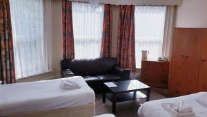 a hotel room with two beds and a leather couch at Medehamstede Hotel in Shanklin
