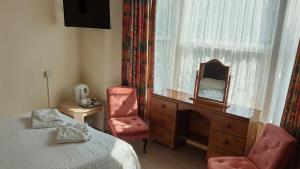 a room with a bed, chair and a lamp at Medehamstede Hotel in Shanklin