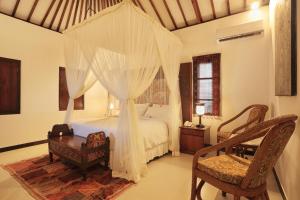 a bedroom with a canopy bed with a desk and a chair at Puri Mas Boutique Resort & Spa in Senggigi