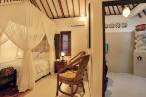 a bedroom with a bed and a chair and a window at Puri Mas Boutique Resort & Spa in Senggigi