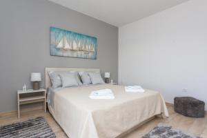 a white bedroom with a large bed with two towels on it at Apartments Maximus in Dubrovnik