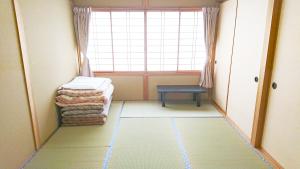 um pequeno quarto com uma janela e uma pilha de cobertores em Guest House 合歓木（ねむ） em Hokuto