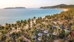 an aerial view of a beach with palm trees and the ocean at Nacpan Beach Glamping in El Nido