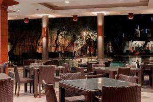 a restaurant with tables and chairs and a pool at Surya Kencana Seaside Hotel in Pangandaran